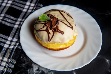 High resolution photography of fresh homemade donut covered with white chocolate on black table.