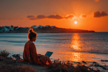 Freelancer digital nomad working with a laptop on the beach during sunset