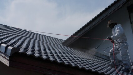 Two men painting a roof of a house .