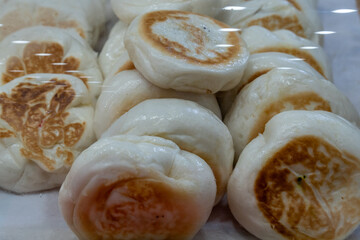 Freshly steamed buns displayed at a local market during a sunny morning in a bustling neighborhood