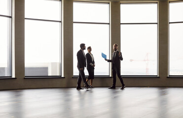 Business professionals in suits walking through spacious modern office with panoramic windows....
