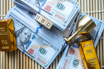 stacks of dollars and gold bars wooden background