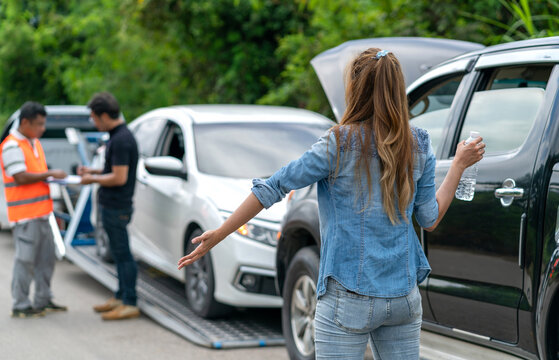 asian woman car broke drinking water waiting for mechanic. female driver having car problem holding water bottle while insurance company working. asian woman drinking water waiting for insurance man