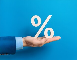 A hand in a suit holds a white percentage symbol against a blue background.