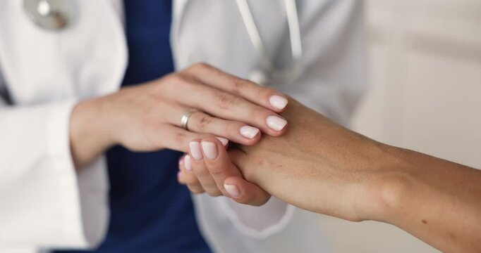 Close up of compassionate gesture between doctor and patient, female therapist or psychologist gently placing her hand over patients arm, as symbol of empathy and psychological support during visit
