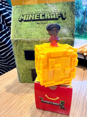 Naklejka premium Colorful Minecraft figure on yellow block with red box in McDonald's, collaboration showcasing creativity concept