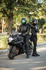 man and girl in helmets standing near motorcycle on open road