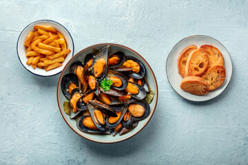 Mussels with French fries and toasted bread, moules frites, overhead flat lay shot on a slate background, seafood appetizer