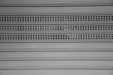 corrugated Grey metal mesh curtain door entrance to the store. Perforated gray silver iron Steel...