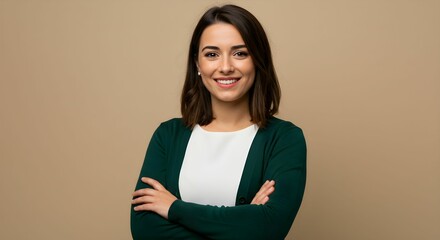 Cheerful Hispanic woman standing against a beige background. Her arms are crossed.