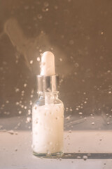 A glass bottle with a pipette and a white moisturizing serum. Cosmetic products. A vial with an...