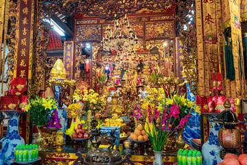 Intricate Vietnamese temple altar, displaying offerings, ornate carvings, and religious statues with vibrant colors.
