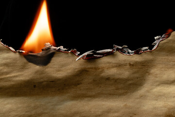 burning old brown paper, glowing edge of paper on a black background.