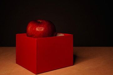 Red apples and red boxes on a black background, with dim lighting to simulate a chiaroscuro effect