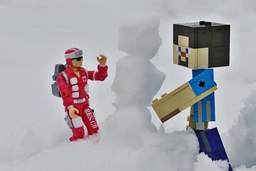 Fototapeta premium LEGO Minecraft figure of Steve and GI JOE medic Lifeline, version from year 1986 building a snowman together. 