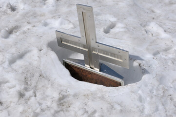 Christian summit cross snow and frost submerged, shiny metal in sunny landscapes after a cold...