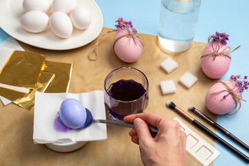 Happy Easter! Close-up of woman's hands painting an easter egg. Decorating Easter Eggs with Flower Sprigs. Step by step instructions. DIY concept.