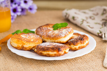 Cottage cheese pancakes with dried apricots and honey on a wooden table