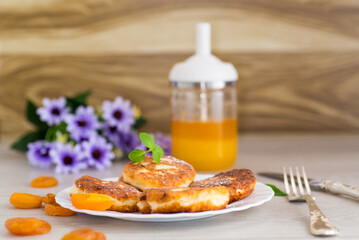 Ruddy cheese pancakes with honey and mint in a white plate