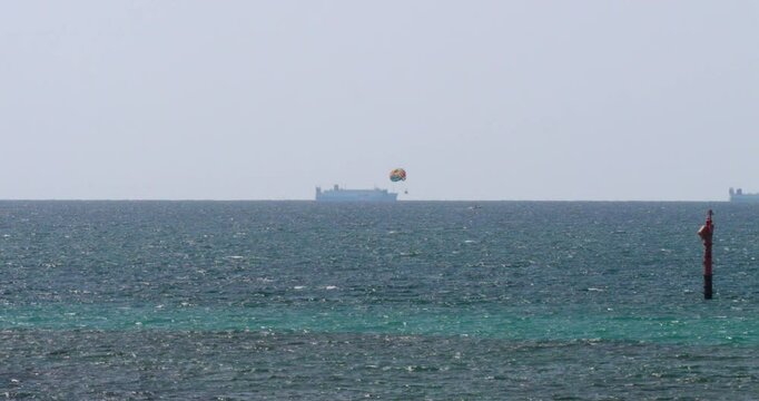 沖に船とパラセーリングが見える海の風景。