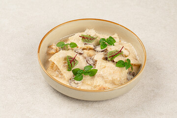 Portion of gourmet ravioli with cream sauce and olives