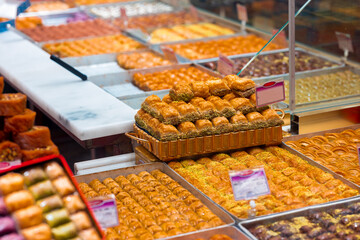 A variety of traditional Turkish baklava and sweet pastries arranged in metal trays in a local dessert shop. Rich in syrup and nuts, ideal for culinary themes.