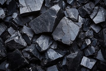 Large pile of broken dark stones with rough edges and deep texture