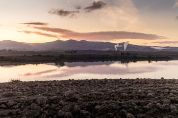 The lake of Santa Luce in the Tuscan countryside during a colorful sunrise with the typical landscape of hills and trees
