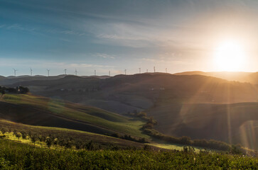 Wind turbines on top of the rolling hills of the Tuscan countryside early in the morning