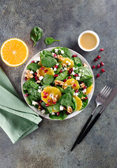 Vegetarian green salad with spinach, oranges,, walnuts and feta cheese on gray background. Top view. 