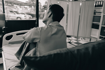 Lonely man silhouette sitting on the bed feeling depressed and stressed in the dark bedroom, Depression and anxiety disorder concept