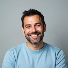Middle-aged man smiling in blue sweater. Portrait of happy, mature male with positive emotion. Smiling face with teeth, beard, black hair. Studio shot on grey background.