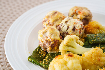 Close-up of meatballs, roasted cauliflower, and green beans on a plate.