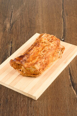 Baked pork meat on a wooden cutting board.