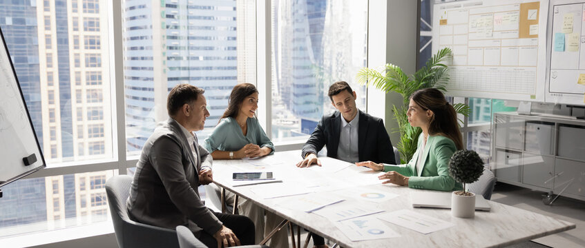 Business team talking at table in meeting room, discussing job tasks, teamwork in modern office workspace, sharing ideas for brainstorming. Stakeholders planning cooperation, marketing strategy