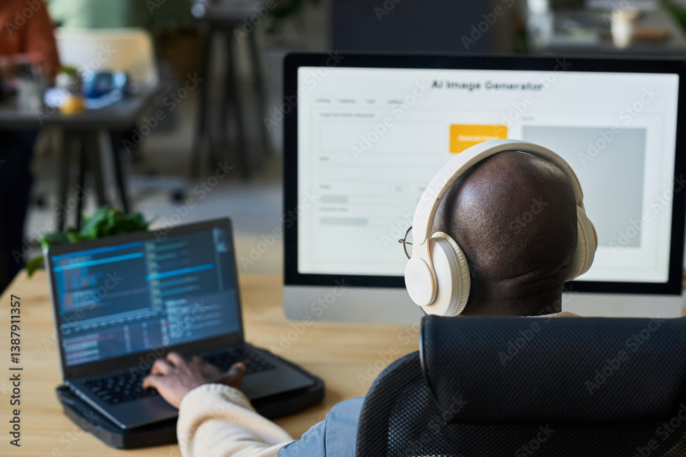 Fototapete Focus on bald head of young male programmer in headphones typing on laptop keypad while decoding data by workplace