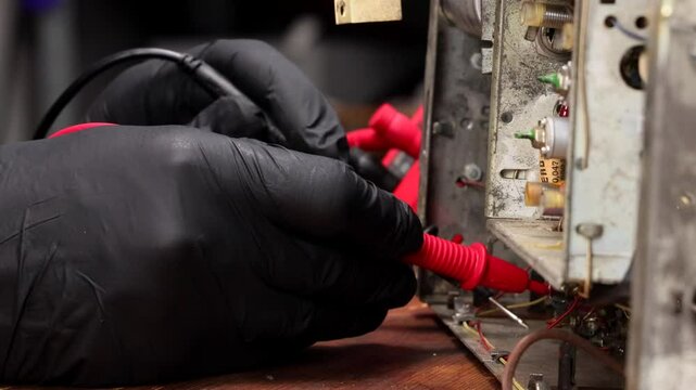 Repair Technician in Black Gloves Measuring Values on Vintage Item with Multimeter