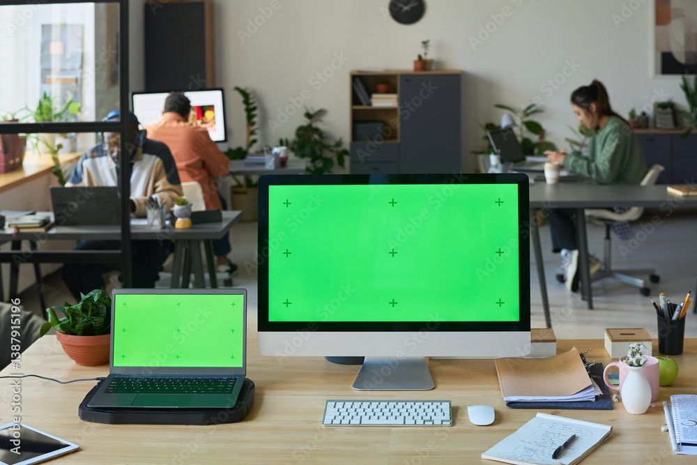 Poster Two computers with chromakey screens standing on desk against group of coworkers networking in modern spacious office