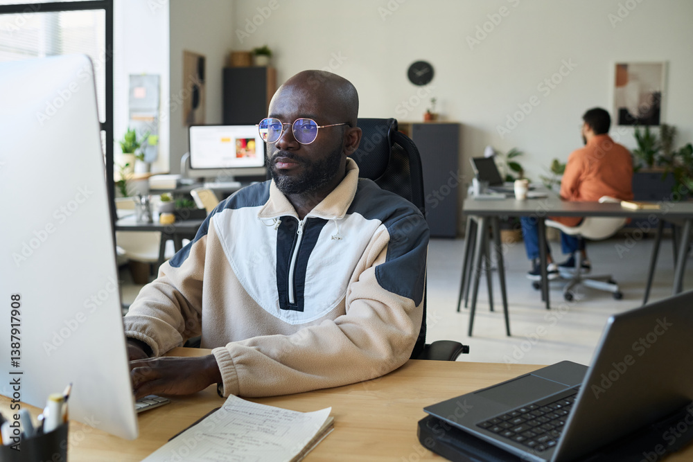 Poster Serious male programmer typing on computer keypad and looking at screen while decoding data or generating new content