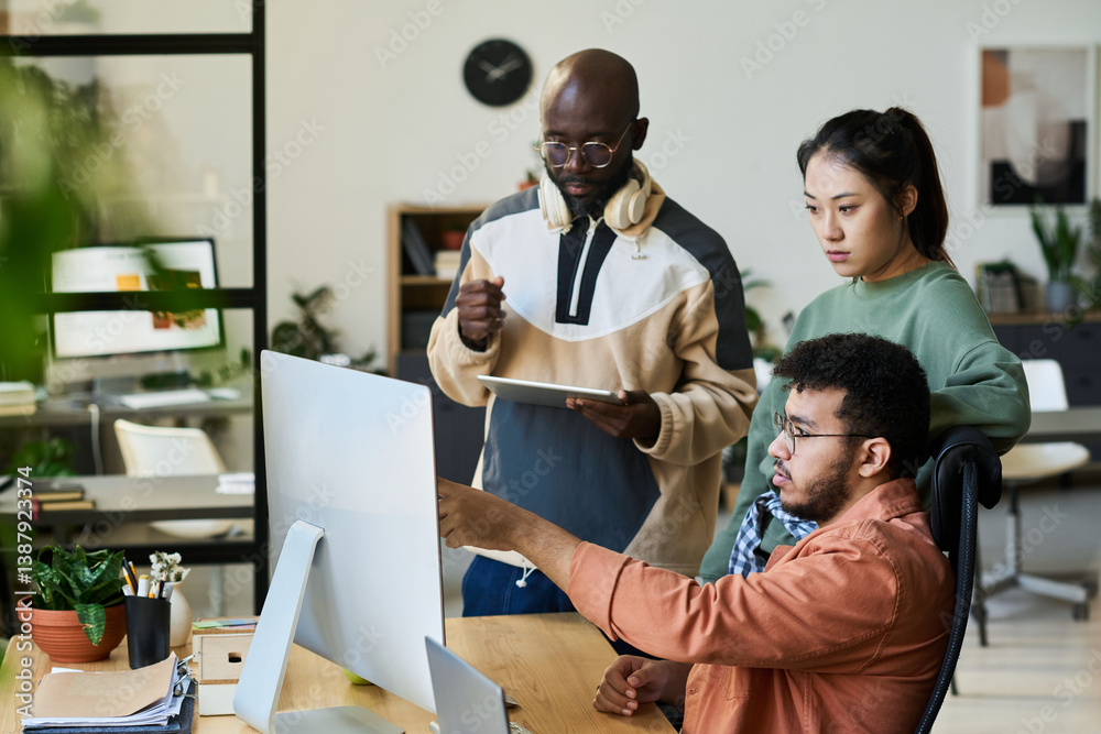 Aufkleber Group of young colleagues looking at screen of desktop computer while one of them pointing at new software product