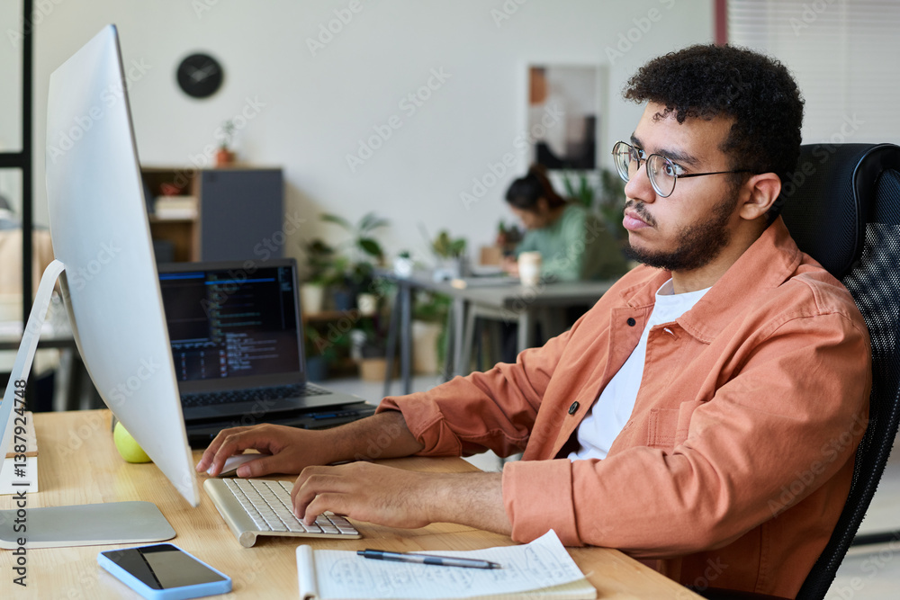 Aufkleber Serious young male software developer or designer pressing keys of computer keypad and looking through online information