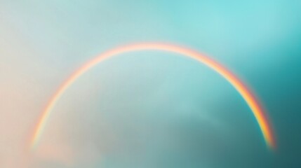 Fototapeta premium A vibrant rainbow arcs across a soft, cloud-filled sky, creating a serene and colorful natural spectacle.