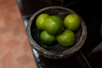 lemon and lime in wooden bowl on tiled floor
