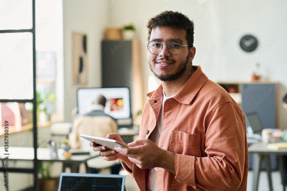 Poster Young smiling male programmer or software developer looking at camera while working over new project in coworking space
