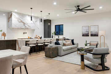 A cozy living room with a couch, chairs, table, and ceiling fan