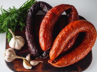 three rings of different sausages on a wooden board on a white background