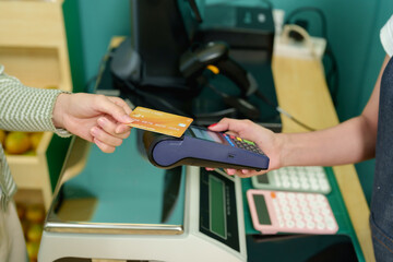 Closeup of hands during contactless credit card transaction at counter in modern tropical fruit store emphasizing digital cashless payment concept in local eco-friendly small business environment