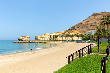Sun loungers and umbrellas on sea beach on sunny day. One of best resorts in the Gulf of Oman