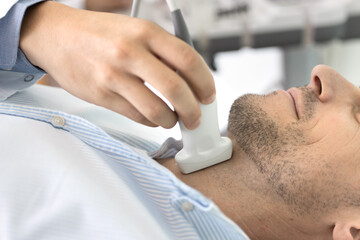 Close up shot of male undergoing thyroid ultrasound examination in clinic. GP professional using...
