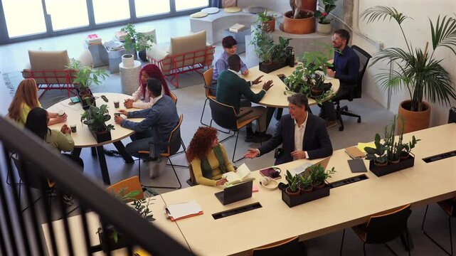 Professional business team engaging in collaborative project discussion within sleek coworking space. Sharing innovative ideas while demonstrating collective workplace synergy and dynamic interaction